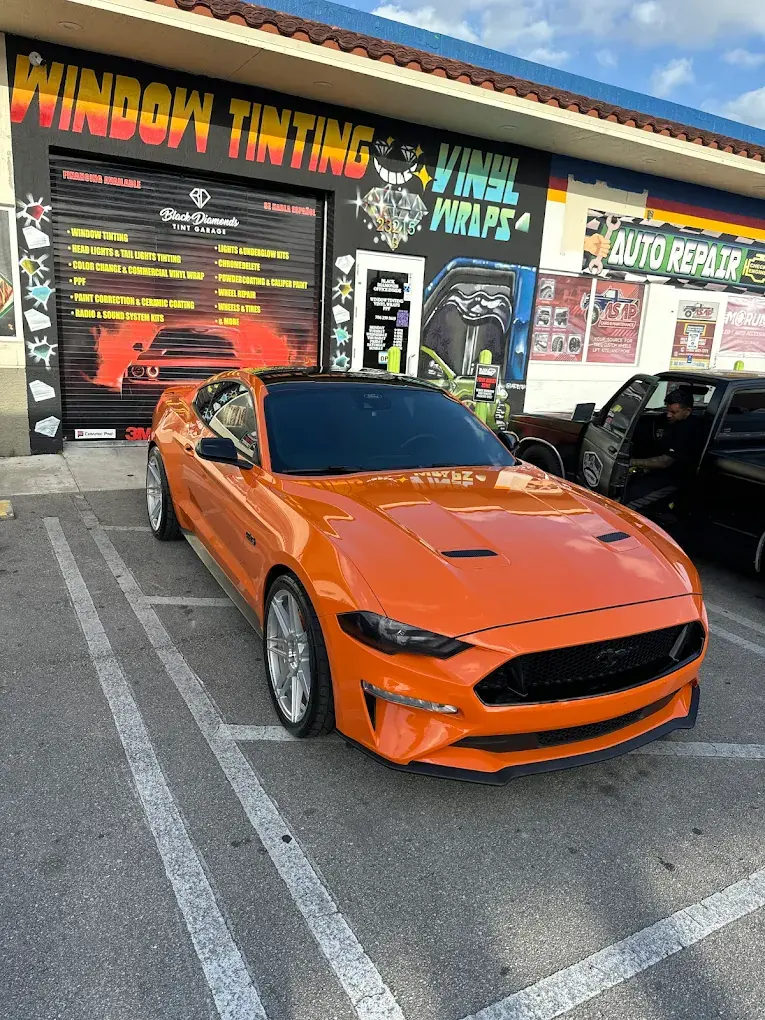 Orange Mustang getting window tint at the shop
